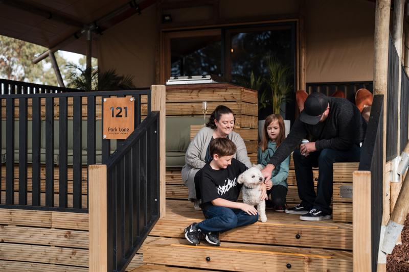 Family and dog sitting on the front deck of a luxury safari tent in Phillip Island